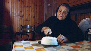 Eine Frau schneidet einen Käselaib an. | Bild: BR