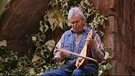 Ein Mann spielt mit einem Bogen auf einem kleinen Saiteninstrument | Bild: BR