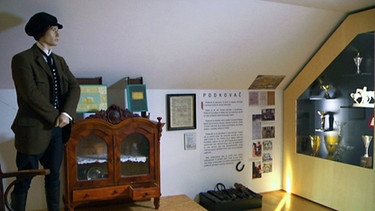Ein Museumsraum mit Ausstellungsstücken und einer Figur | Bild: BR