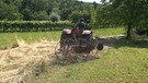 Ein Mann wendet mit einem Traktor Heu | Bild: BR