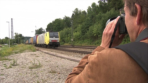 Ein Mann fotografiert einen Zug | Bild: BR