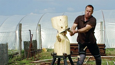 Zoltan Bozso schlägt mit einer Axt in einen Holzblock | Bild: BR
