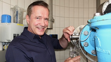 Alexander Herrmann zapft an der Quelle ein Glas Wasser bei der Siegsdorfer Petrusquelle (Lkr. Traunstein, Oberbayern). | Bild: BR/Jürgen Endriß