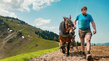 Bäne, Bergmensch der Staffel 11, führt eines seiner Pferde beim Ackern | Bild: BR/Luis Trautmann