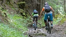 Zwei Mountainbiker fahren auf einem steinigen Waldtrail abwärts | Bild: BR/Georg Bayerle