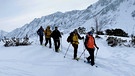 Eine Gruppe Schneeschuh-Wanderern in verschneiter Berglandschaft | Bild: BR/Kathrin Denk