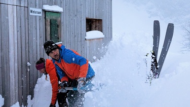 Zwei Skibergsteiger schaufeln den Eingang des Winterraums frei | Bild: BR/Thomas März