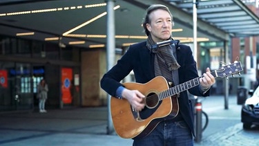 Jochen Distelmeyer mit Gitarre vor einem Kaufhaus | Bild: BR