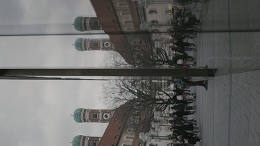 Ein auf 270 Grad gedrehtes Foto von der Münchener Innenstadt. In der Mitte spiegelt sich das Bild durch eine Glasfassade. | Bild: BR
