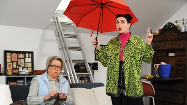 Dahoam is Dahoam: Tina (Anita Eichhorn, rechts) provoziert Margots (Sarah Camp, links) Aberglauben, indem sie in der Wohnung einen Regenschirm aufspannt.
| Bild: BR/Marco Orlando Pichler