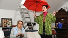 Dahoam is Dahoam: Tina (Anita Eichhorn, rechts) provoziert Margots (Sarah Camp, links) Aberglauben, indem sie in der Wohnung einen Regenschirm aufspannt.
| Bild: BR/Marco Orlando Pichler