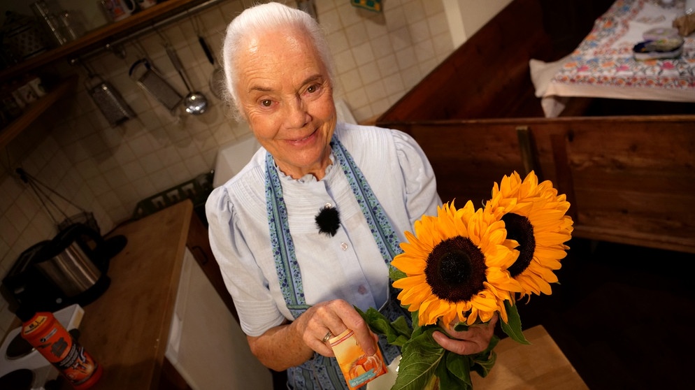 Dahoam is Dahoam: Uri (Ursula Erber) mit Sonnenblumen und einem Päckchen Backpulver. | Bild: BR