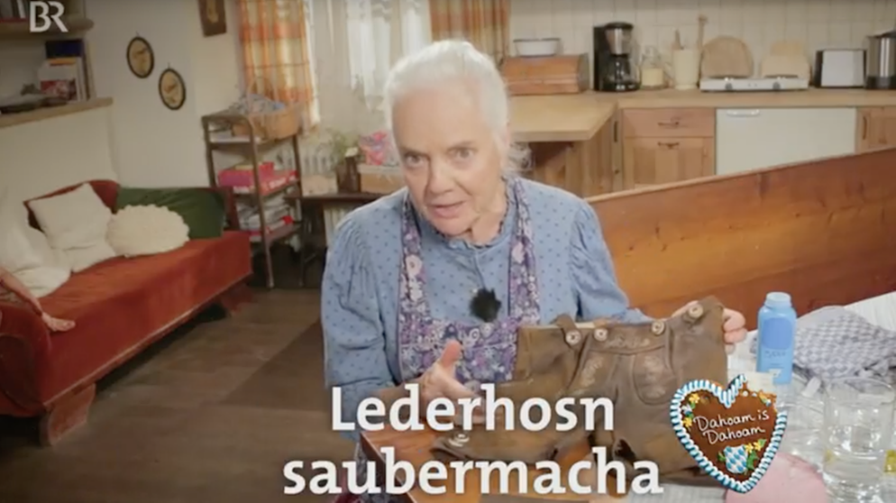 Theres (Ursula Erber) erklärt, wie man ganz leicht eine verschmutzte Lederhose zuhause reinigt. | Bild: Markus Walsch / BR