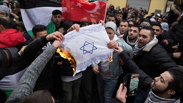 Teilnehmer einer Demonstration verbrennen am 10.12.2017 eine selbstgemalte Fahne mit einem Davidstern in Berlin im Stadtteil Neukölln.  | Bild: picture alliance / Jüdisches Forum für Demokratie und gegen Antisemitismus e.V./dpa | -