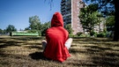 Jugendlicher sitzt im Rasen vor einem Plattenbau | Bild: picture alliance / ZB | Thomas Eisenhuth