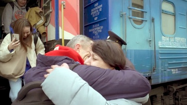 Ein Mann und eine Frau umarmen sich an einem Zug. | Bild: BR