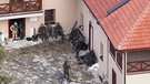 Militärisch ausgerüstete Personen im Innenhof eines Hauses | Bild: BR