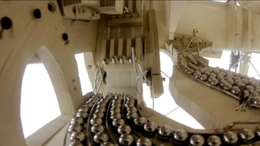 Murmeln liegen im Inneren der Maschine auf Schienen | Bild: BR