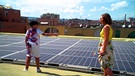 Ein Junge und eine Frau vor Sonnenkollektoren | Bild: BR