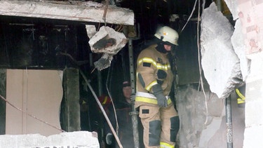 Eine Feuerwehrmann in einem zerstörten Gebäude | Bild: BR