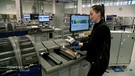 Eine Mitarbeiterin des Chip-Karten-Herstellers legt Karten-Rohlinge in eine Maschine ein. | Bild: BR
