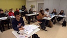 Angeworbene Fachkräfte aus dem Ausland sitzen im Unterricht. | Bild: BR