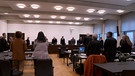 Die Anwesenden im Gerichtssaal erheben sich zum Beginn des Prozesses. | Bild: BR