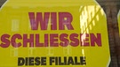 Schild in Schaufenster mit "Wir schließen diese Filiale". | Bild: BR