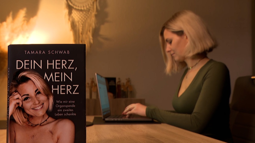 Buch von Tamara Schwab im Vordergrund und Tamara Schwab im Hintergrund am Laptop-sitzend. | Bild: BR