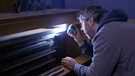 Inspektion der Orgel mit einer Taschenlampe. | Bild: BR