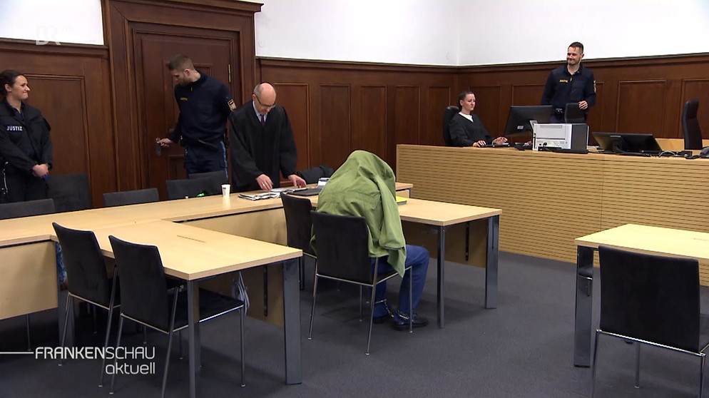 Angeklagter versteckt sich in Gerichtssaal unter seiner Jacke. | Bild: BR