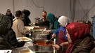 Frauen verteilen Essen an der Essensausgabe. | Bild: BR