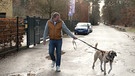 Ein ehrenamtlicher Gassigeher mit einem Hund an der Leine. | Bild: BR
