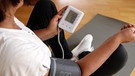 Eine Frau misst ihren Blutdruck. | Bild: BR