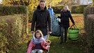 Moderator Fero Andersen hilft Familie Hussock das Laub von der Wiese vorm Vereinsheim in die Gartenlaube zu transportieren.  | Bild: BR