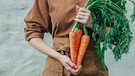 Frau hält Karotten in der Hand. | Bild: picture-alliance/dpa