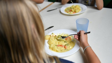 Ein Mädchen isst in der Schule. | Bild: picture-alliance/dpa