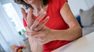 Eine Frau in einem roten Kleid reibt sich die Hände. | Bild: picture alliance/dpa/Christin Klose