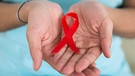 Die rote Schleife steht als Symbol für die Immunschwächekrankheit AIDS. | Bild: picture alliance/Andriy Popov