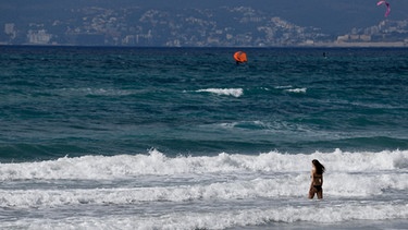 11.03.2021, Spanien, Palma: Eine Frau geht am Strand von Arenal zum Schwimmen in die Wellen. Deutsche Reiseveranstalter hoffen, dass sie Urlauber ab den Osterferien wieder nach Mallorca bringen können. Foto: Clara Margais/dpa - ACHTUNG: Namen auf den Röhrchen wurden aus rechtlichen Gründen gepixelt +++ dpa-Bildfunk +++ | Bild: dpa-Bildfunk/Clara Margais