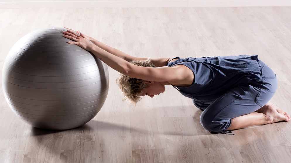 Frau mit Gymnastikball bei Rückenübung | Bild: picture alliance / Shotshop | Photology2000
