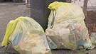 Zwei gelbe Säcke stehen neben einer Mülltonne. Viele Kunststoffe lassen sich nicht sortenrein sortieren. Verpackungen mit fluoreszierenden Markern könnten diesen Job übernehmen.  | Bild: BR/Gut zu wissen