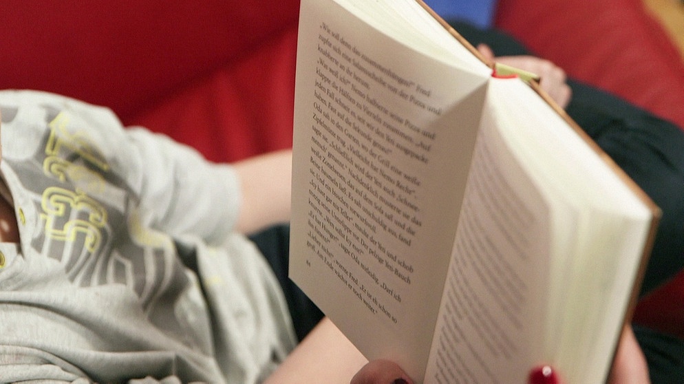 Mutter liest ihrem Kind ein Buch vor. | Bild: BR