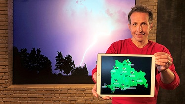 Willi Weitzel mit Wetter-App und Gewitterstimmung im Hintergrund. Bessere Vorhersage bei Starkregen | Bild: BR/Gut zu wissen