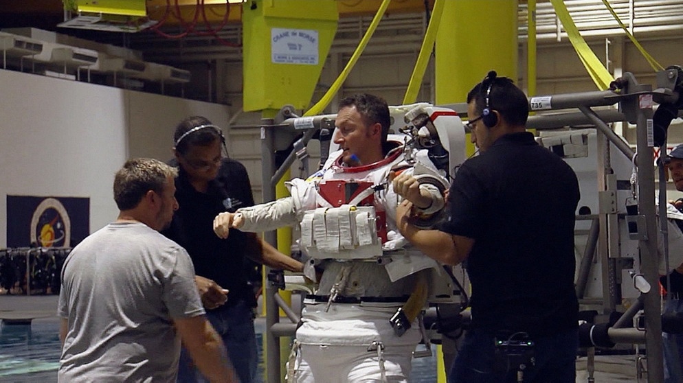 ESA-Astronaut Matthias Maurer wird der Raumanzug angezogen, damit er in einem Wasserbecken für die Schwerelosigkeit trainieren kann. | Bild: BR
