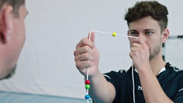 Neueroathletik-Trainer macht eine Augen-Gehirn-Übung mit einem Patienten. | Bild: BR