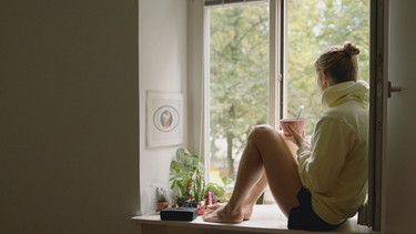 Frau sitzt gelassen und entspannt am Fenster. Stabil und gelassen: Wie trainiere ich Resilienz? | Bild: BR/Gut zu wissen