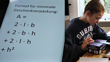 Geteiltes Bild: Matheformel für minimale Geschenkverpackung und Mädchen das ein Verpackung ausmisst.  | Bild: BR/Gut zu wissen