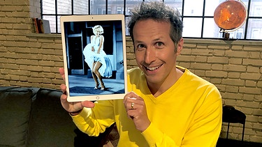 "Gut zu wissen"- Moderator Willi Weitzel hält ein Bild auf dem IPad von Marilyn Monroe hoch. Über 3 Millionen Dollar brachte das weiße Kleid, das Marilyn Monroe auf diesem legendären Foto trug, bei einer Auktion ein. Es gibt jedoch noch kostbarere Kleider.  | Bild: BR/Gut zu wissen