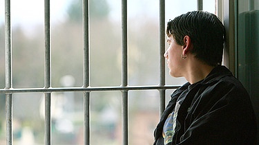 Symbolbild: Ein jugendlicher Insasse einer Justizvollzugsanstalt sitzt auf einer Fensterbank und schaut aus dem Fenster | Bild: picture-alliance/ dpa | Fredrik von Erichsen